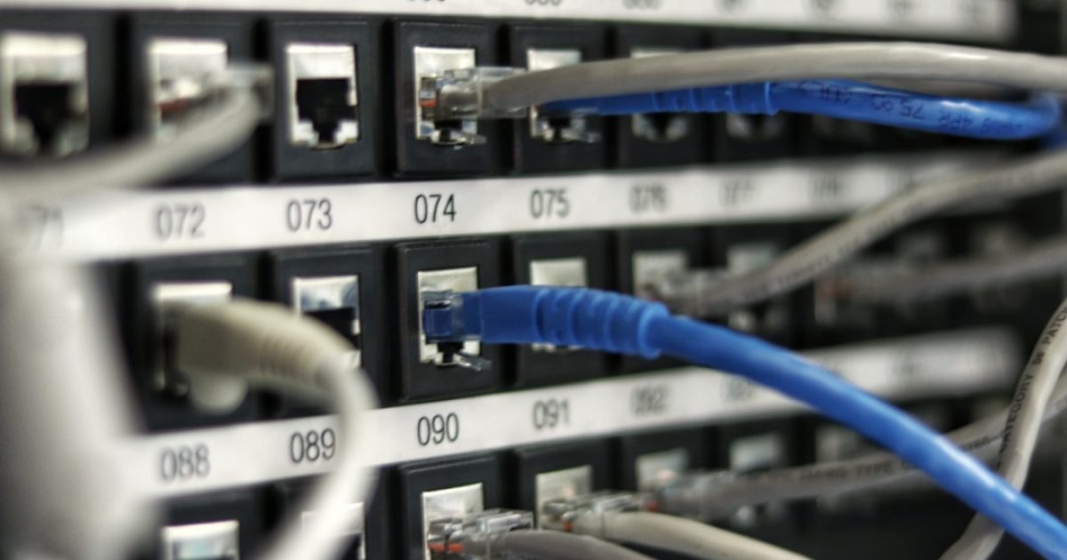 Pessoa a trabalhar num computador portátil com um diagrama de registos DNS complexos e setas azuis a ligar diferentes serviços web, simbolizando a gestão de domínios.