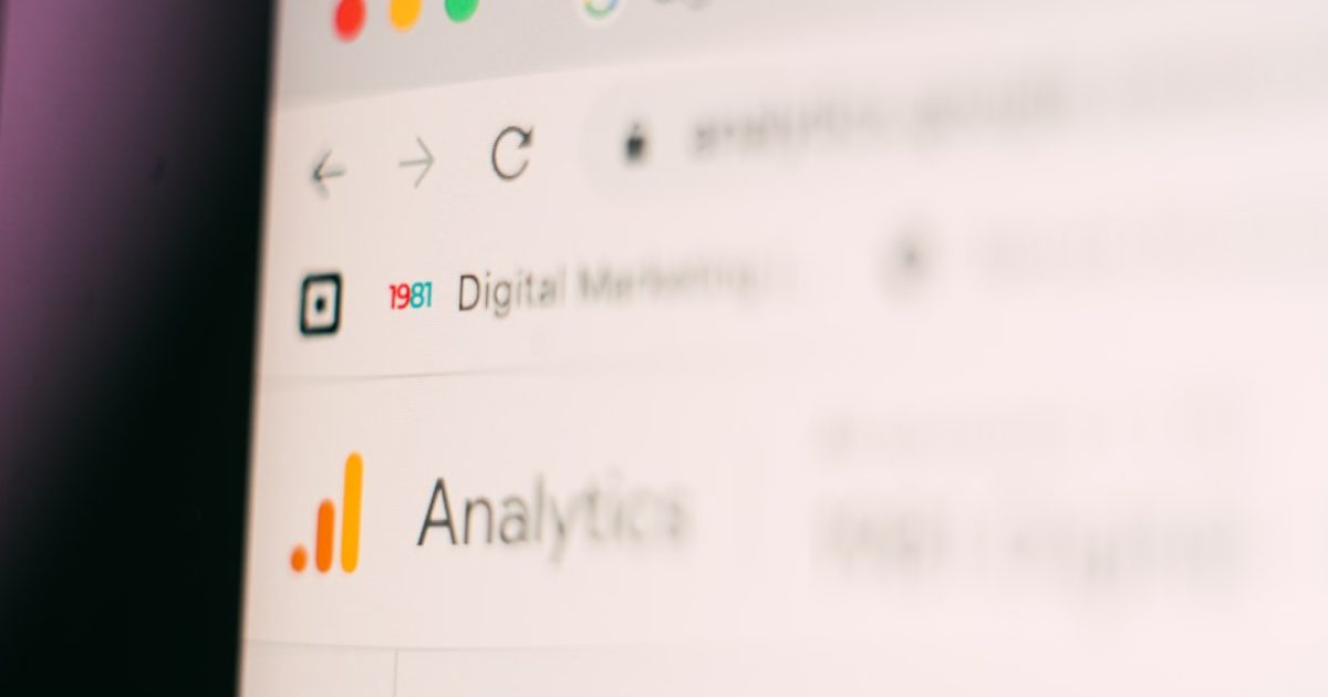 Gráfico de barras e linhas do Google Analytics 4 num ecrã de computador, com uma mão a apontar para dados relevantes.